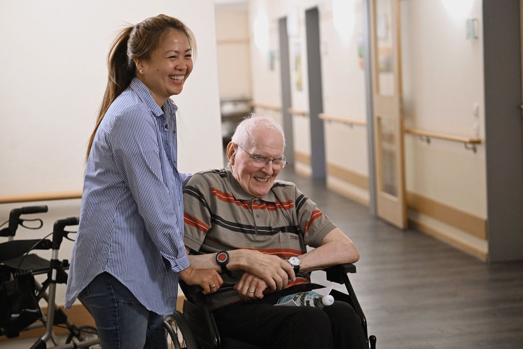 Pflegerin mit aelteren mann in rollstuhl